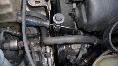 photo 1: ratchet (using a torque wrench because it was longer) pulled back and locked in place with screwdriver against body and timing belt cover (belt was removed before photo was taken).