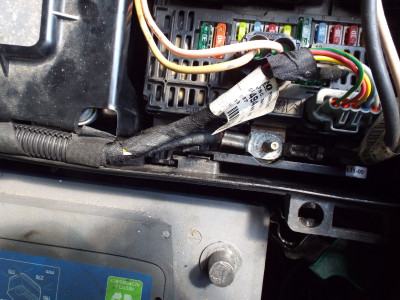 Bottom left latch holding fuse box in place (just below the cable on the bolt)