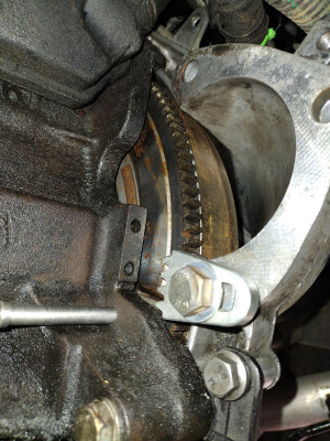 Flywheel locking tool in starter motor bottom hole with M10 bolt and washers to ensure sat flat
