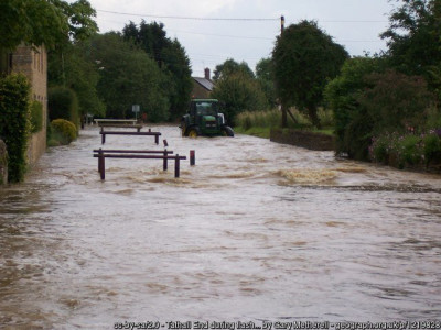 Tathall End during flash flood, Summer 2007<br />The tractor gives an indication of water depth on the road. Local residents described this as the highest water level reached in over 30 years, and followed just two 10 minute thunderstorms. Geograph Stamped image